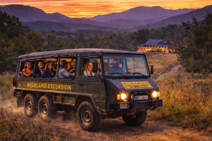 Group on a Highland Excursion truck at sunset with scenic mountain backdrop.