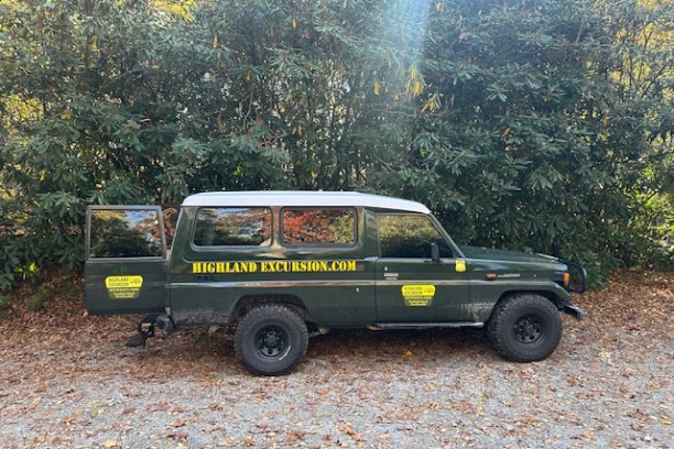 Green excursion vehicle parked on gravel with forest background, displaying 'Highland Excursion.com' on the side.